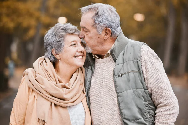 Love, kiss and senior couple in park enjoying weekend, quality time and romantic bonding together. Retirement, relationship and elderly man and woman walking, hugging and embrace outdoors in nature.