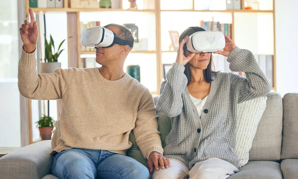 Virtual reality, 3d and a couple in the interactive metaverse while together on a sofa in the living room of a home. VR, goggles and gaming with a man and woman in their house to relax or video game.