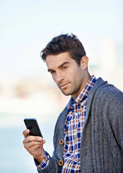 This phone has everything I need. a handsome young man text messaging on his mobile phone outdoors
