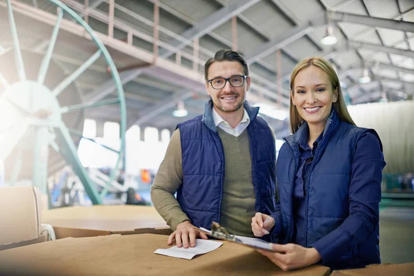 stock image We make logistics look easy. Portrait of a two managers reading paperwork while standing on the factory floor