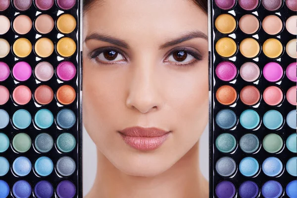 No day should be without color. Studio shot of a beautiful woman with makeup palettes in front of her face