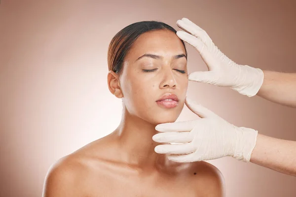 Plastic surgery, woman and doctor hands check face for botox, beauty implant and makeup cosmetics. Skincare consultation, facial and gloves for aesthetics, filler and body change on studio background.