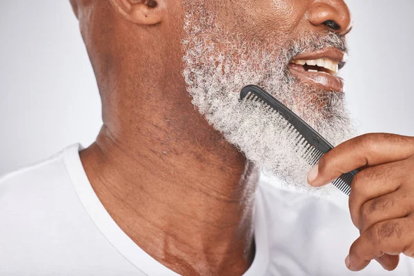 Elderly, black man and comb for beard, beauty and grooming with hygiene and cleaning face zoom. Hair care, brush body hair and wellness with cosmetic care and natural against studio background.