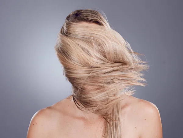 Hair care, back view and blonde woman with long healthy hair from a keratin, brazilian or botox treatment. Beauty, cosmetic and girl model with a shiny and glossy hair style by gray studio background.
