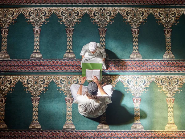Muslim pray, child or man in praying with Quran for peace, mindfulness or support from Allah in holy mosque. Top view, Islamic kid or person studying or praying to help worship God on Ramadan Kareem.