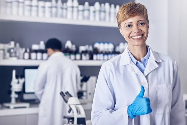 Science, thumbs up and research, portrait of woman pharmacist or healthcare scientist in laboratory. Medical innovation, analytics and success, happy woman pharmaceutical medicine employee with smile.
