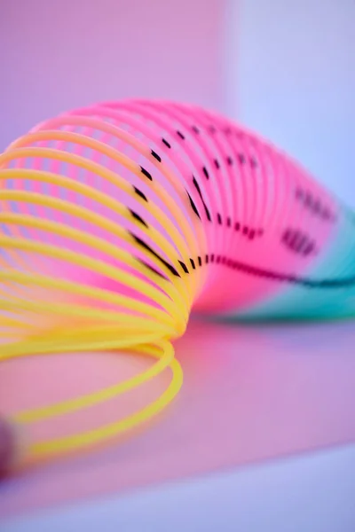 Rainbow, slinky toy and color spiral in studio for neon background for flexible, abstract or creative vaporwave aesthetic wallpaper. Colorful plastic spring backdrop for art, relax and happiness.