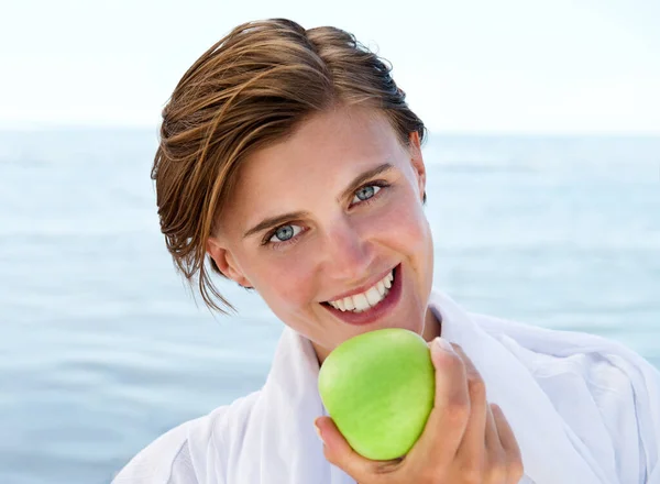 Having a bite at the beach. An attractive young woman taking a bite from a green apple