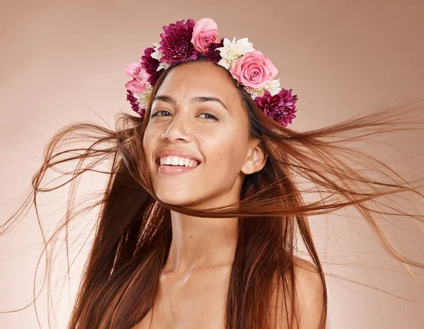 Woman, portrait and flowers on crown, studio background and windy hair for healthy skincare in Brazil. Happy face, floral headband and model of beauty, spring fashion and natural makeup of eco plants.