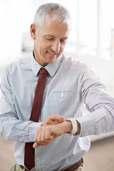 Right On Time. a mature businessman using a smart watch