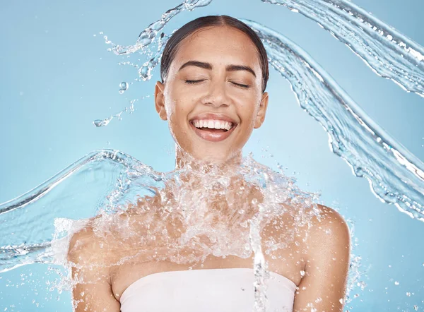 Happy woman, face or water splash skincare on blue background studio in healthcare wellness, Brazil hygiene cleaning or relax grooming. Beauty model, wet or water drops shower for facial dermatology.