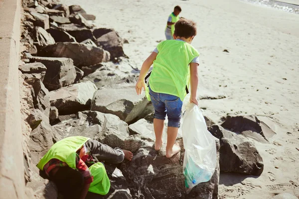 Environment, cleaning and children with dirt on beach for clean up, pollution and eco friendly volunteer. Sustainability, recycle and kids reduce waste, pick up trash and plastic bag on beach sand.