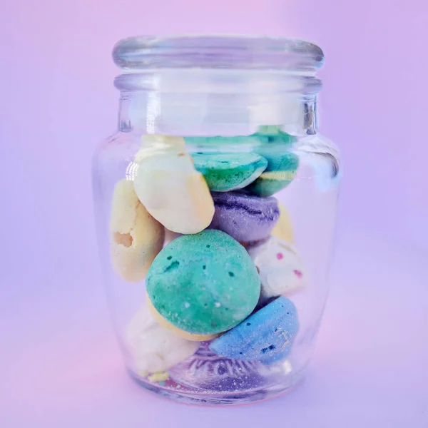 Glass jar, beach stones or rocks on table in studio isolated on a purple background. Beauty, art and variety of colorful pebbles in bottle collected from sea or ocean coast for interior decoration