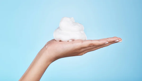 Skincare, wellness and hands with foam on blue background for treatment, grooming and body care. Cosmetics, spa aesthetic and palm with shaving cream, soap and cleaning products isolated in studio.