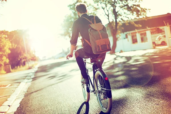 Carefree and carbon free. Rearview shot of a young man riding a bicycle outdoors