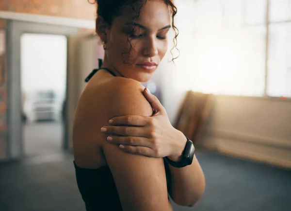 Woman, fitness and shoulder injury from sports workout, exercise or training at the gym indoors. Female holding arm after painful sport accident, inflammation or bruise from intense exercising.