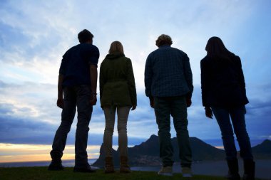 Majestic views...A group of young adults watching the sunset from a high viewpoint clipart