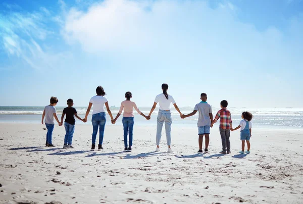 Support, back and big family holding hands at the beach, summer walking and travel holiday in nature of Portugal. Hope, love and women with affection for adopted kids on a vacation at the ocean.