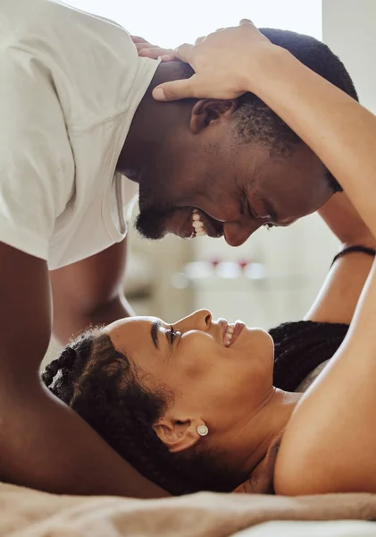Black couple, love and home bedroom romance while happy and intimate together on bed at home, apartment or hotel. Face of young man and woman in happy marriage with commitment and care on honeymoon.