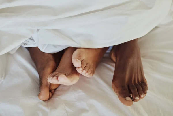 Intimate couple feet in bedroom for love, valentines day and sexual partner with morning passion at home. Top view of man, woman and foot with intimacy, relax and sleeping together in erotic marriage.