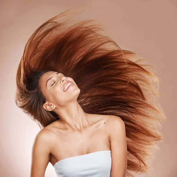 Hair care, wellness and woman in studio with salon, keratin or botox health hair treatment. Cosmetics, happy and female model from Brazil with a long, healthy and brown hair style by brown background.