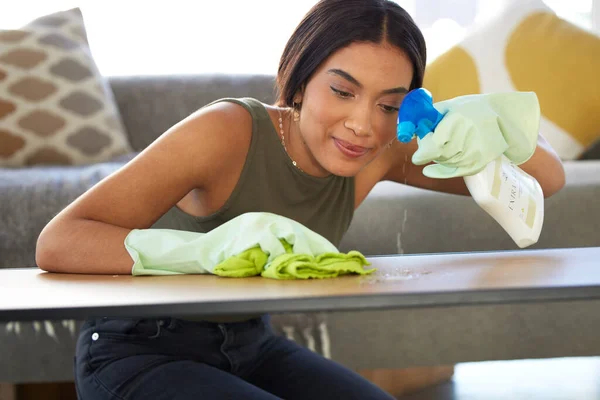 Woman, cleaning service and spraying living room table for bacteria, dust and dirt for health, wellness and safety in house or apartment. Happy cleaner with cloth and chemical liquid bottle to clean.