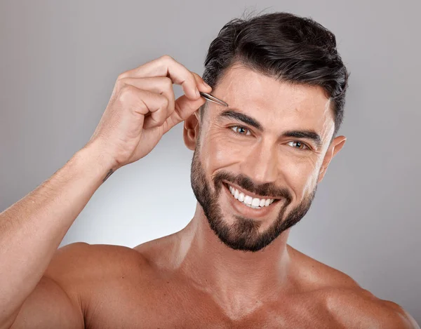Man, eyebrow tweezers and face hair removal for skincare beauty, grooming wellness and hygiene happiness in grey studio background. Model smile, cosmetics facial care and dermatology or microblading.