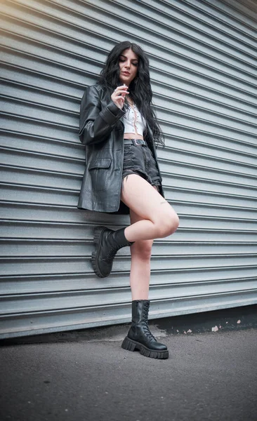 Young woman smoking, fashion and streetwear with gen z punk style, outdoor and trendy, edgy in urban city. Youth, focus and beauty with rock aesthetic, fashion model in designer clothes in London.