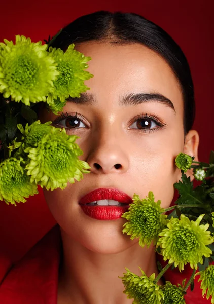Beauty, flowers and face with woman and lipstick, natural cosmetics with nature, skincare and organic treatment against red studio background. Lips, portrait and microblading, eyebrow care and makeup.