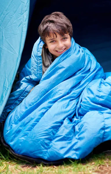 Waking up to a fresh new day...camping rocks. Portrait of a young boy wrapped in his sleeping bag