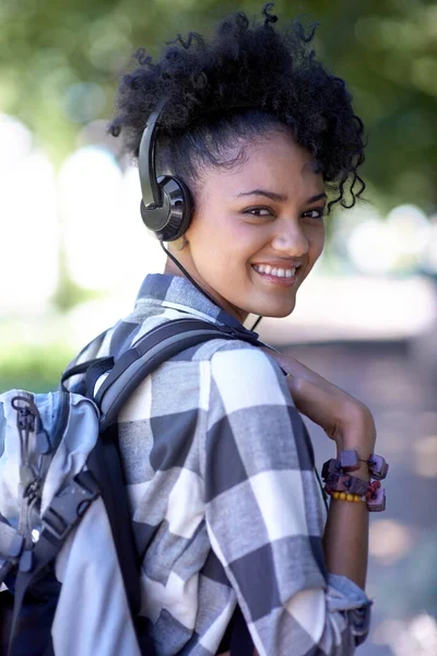 Flashing a genuine smile. A young woman with headphones around her neck