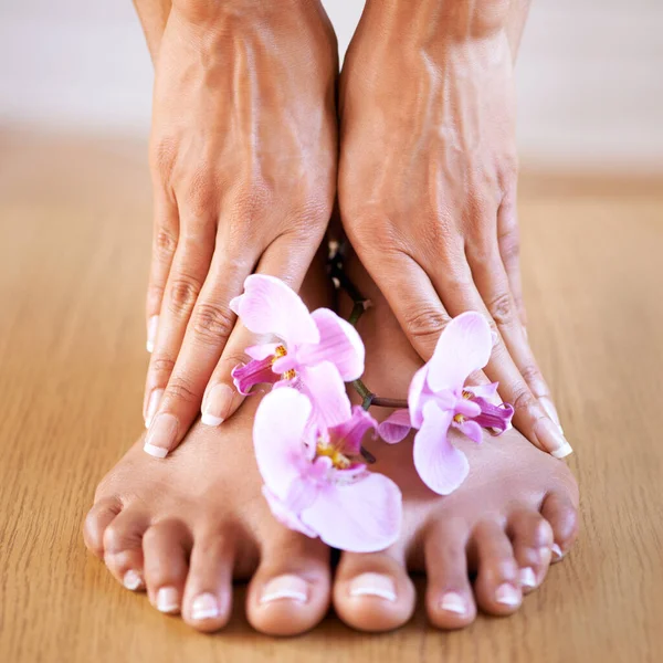 Skincare girl and hands with flowers on feet for luxury cosmetic treatment with manicure and pedicure nails. Healthy skin of black woman with orchid for beauty, wellness and pamper lifestyle