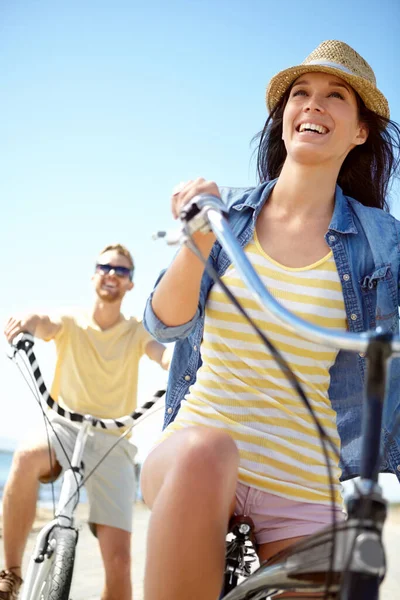 Cycling, travel and couple with a woman on summer vacation or holiday riding on the promenade by the beach. Bike, freedom and date with a girlfriend outdoor for a ride on the coast during the day.