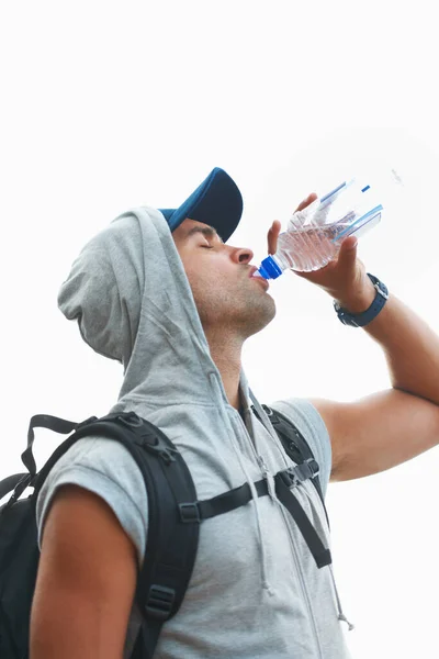 Taking a sip to sustain his stamina. Profile of a young hiker taking a sip of water