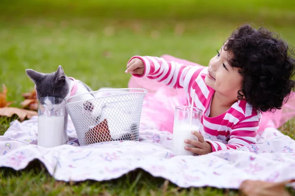 The entire glass Youve got to be kitten me. an adorable little girl drinking milk on the grass next to her kitten