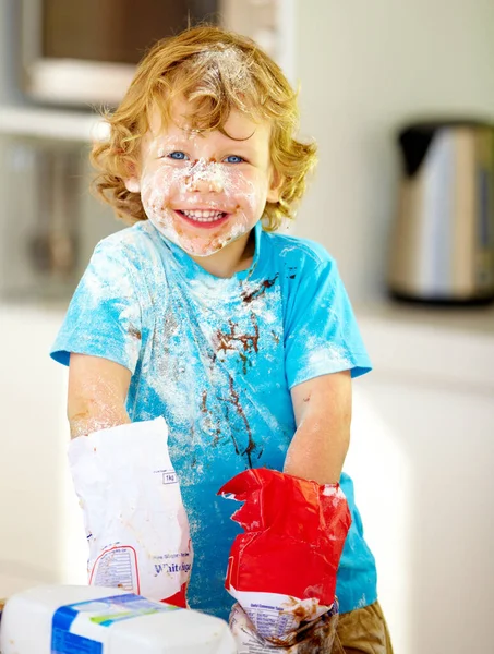The future of the culinary arts. A little boy covered in dough and flour