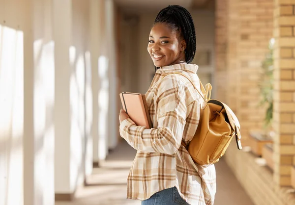 College student portrait, black woman and university with books and backpack while walking at campus. Young gen z female happy about education, learning and future after studying at school building.