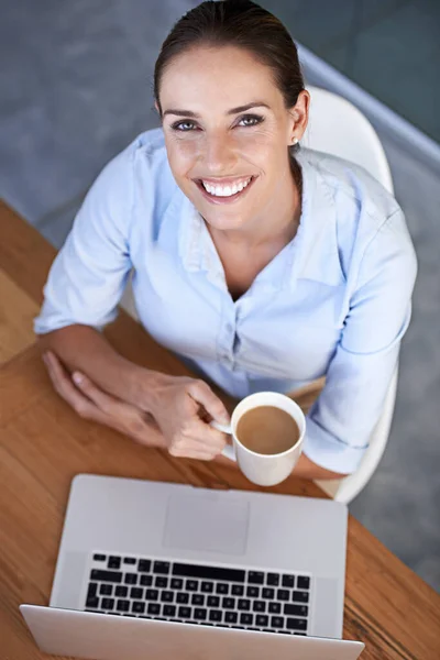Enjoying a much needed cup o joe. High angle portrait of a young businesswoman sitting with her laptop and a coffee