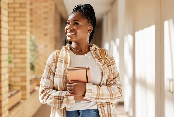 Black woman, college student and thinking about future with books while walking at campus or university. Young gen z female happy about education, learning and choice to study at school building.