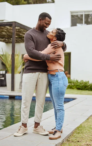 Black couple, house and swimming pool property while outdoor for a hug, love and care while happy about real estate. Man and woman at their new home with pride and smile for mortgage loan approval.