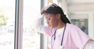 Doctor, woman and burnout by window with stress, headache or sad in hospital workplace with hand on head. Black woman, medic and mental health problem at clinic with anxiety from work in healthcare.