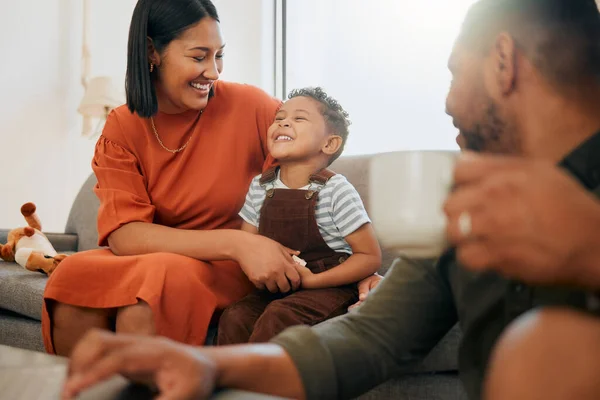 A happy mixed race family of three relaxing in the lounge and being playful together. Loving black family bonding with their son while playing fun games on the sofa at home.