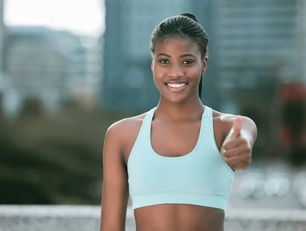 自信に満ちた若いアフリカ系アメリカ人女性が屋外で運動をしながら親指を振る舞います 市内で良いトレーニングワークアウトのためにやる気と準備を探している幸せな女性アスリート — ストック写真