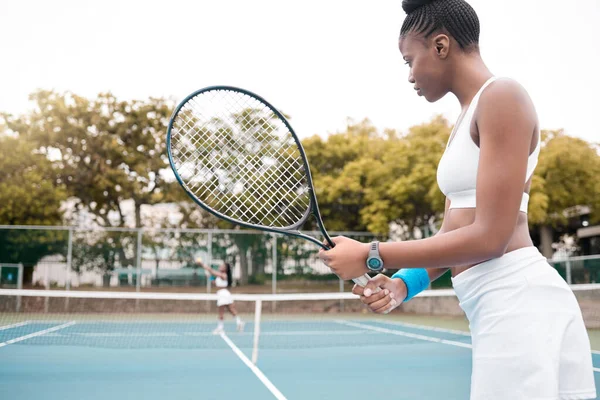 Woman waiting during a tennis match. Young woman playing a game of tennis with a friend. Confident professional tennis player holding her racket during a match. Young girl standing on a tennis court.