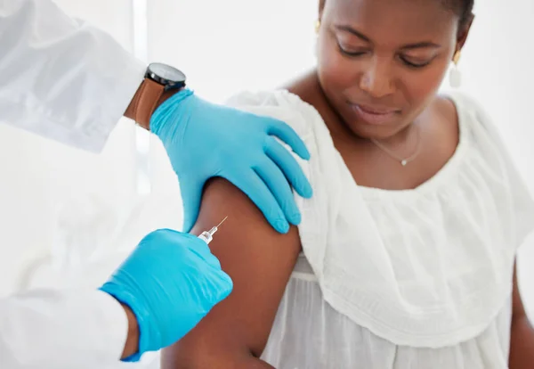 Doctor injecting a patient in the arm. Hand of a doctor injecting a patient with a needle. African american woman being injected with a vaccine. Patient being injected with a cure treatment.