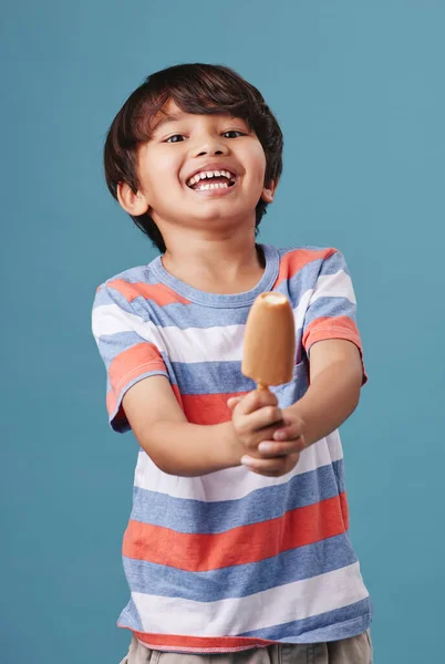 一个可爱的亚洲小男孩在蓝色背景下享受甜蜜待遇的画像 混血儿吃着蘸了糖的冰棒当点心 — 图库照片