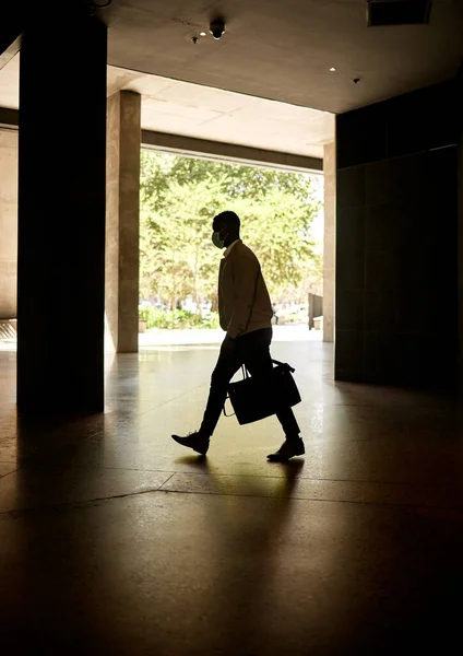 Silhouette of a businessman walking in a station on his way to work in the morning while carrying his bag.