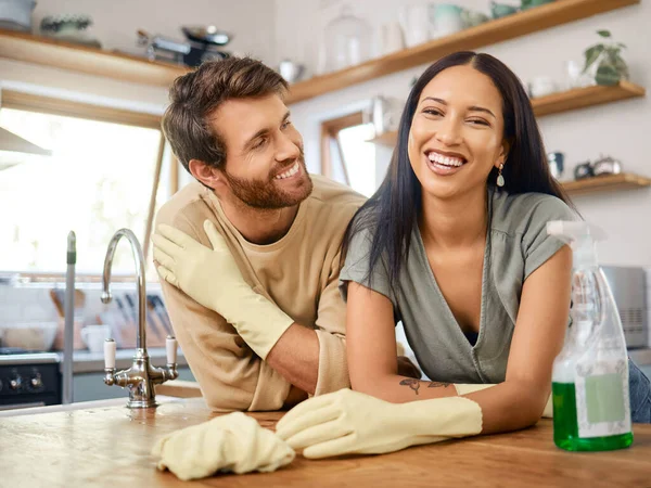 Happy young interracial couple cleaning their home. Young man and woman wearing gloves and using cleaning detergents while doing chores together at home