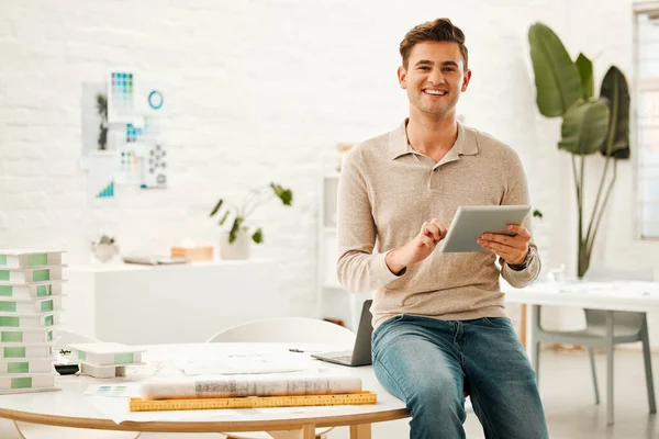 Portrait of a happy businessman using a tablet. Young designer using a wireless online device. Creative entrepreneur working on a digital tablet. Architect in his design agency