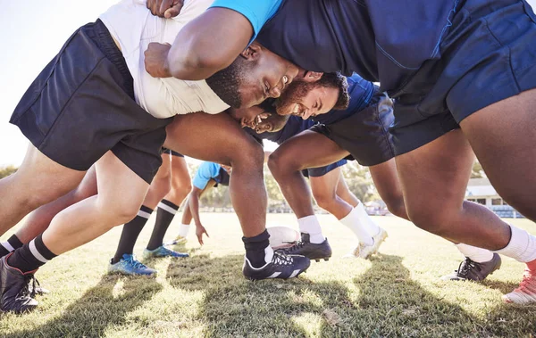 Below two opponent rugby teams contesting a scrum during a match outside on a field. Rugby players battling and fighting to win the ball while competing for possession in a game. Strength and power.